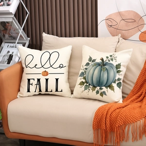 Fall themed pumpkin pillow covers set on sofa with Hello Fall lettering and orange knit blanket
