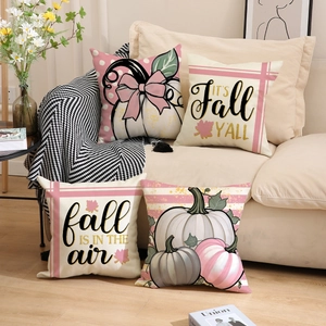 Detail of four fall pumpkin pillow covers in pink and cream on a cozy sofa