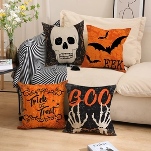 Four Halloween linen pillow covers with skull and bat prints on a cozy sofa