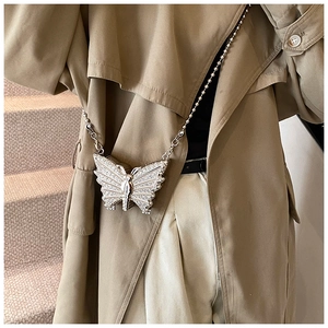 Détail du sac papillon argenté orné de strass avec une fine bandoulière en chaîne billes