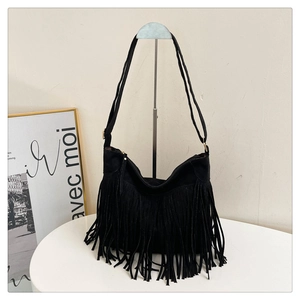 Detail of black suede shoulder bag featuring long fringe tassels and metal zipper hardware