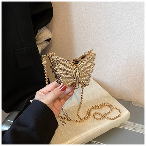 Détail d'une pochette papillon dorée avec strass scintillants et chaîne à perles