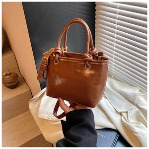 Détail du sac cabas marron avec poignées nouées et anneaux en métal doré