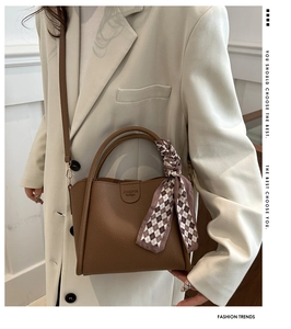 Close-up of brown litchi pattern leather handbag with decorative scarf on the handle