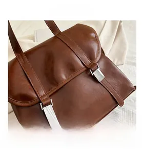 Dettaglio di borsa vintage marrone con fibbie in metallo argentato su tessuto bianco