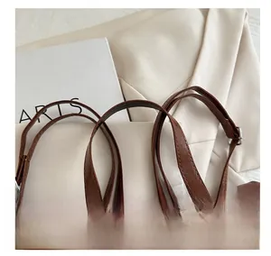 Vista macro di borsa in pelle marrone con cuciture rinforzate e tracolla regolabile