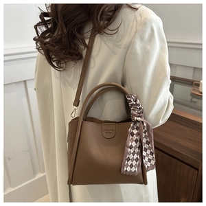 Detailed view of a brown pebbled leather tote bag with silk scarf and thin strap