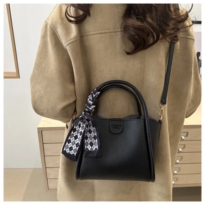 Détail du sac cabas en cuir grainé noir avec foulard à carreaux noir et blanc sur l'anse