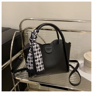 Détail du sac cabas en cuir grainé noir avec foulard décoratif en soie sur la poignée