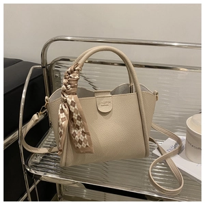 Détail du sac à main beige en cuir grainé avec foulard sur chariot en métal