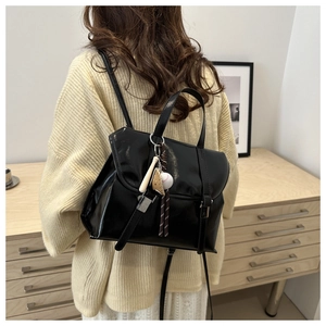 Détail du sac à dos vintage en similicuir noir avec boucles argentées et breloque baseball