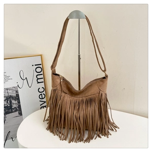 Detail of bohemian khaki suede shoulder bag featuring long fringe tassels and metal hardware