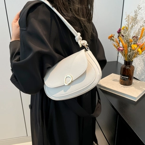 White semi-circle saddle bag with gold buckle and braided knot strap on a model