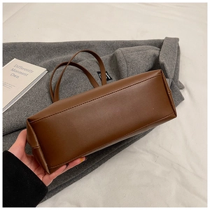 Detailed view of the rectangular bottom structure and fine stitching on the brown tote bag