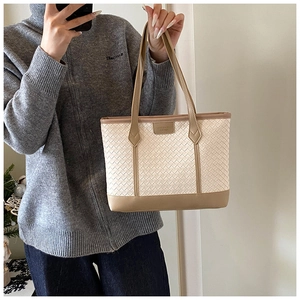 Detail view of woven tote bag showing ivory texture and khaki leather strap