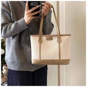 Close-up of retro woven tote bag with brown leather handles and brand tag detailing