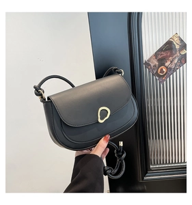 Detail of black saddle bag featuring matte leather and unique gold ring buckle closure