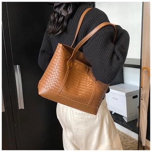 Close-up of brown woven leather tote bag with smooth shoulder straps shown in interior setting