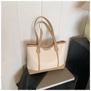 Detail of beige woven tote bag with premium leather trim and large capacity interior