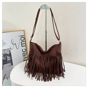 Close-up of brown suede fringe shoulder bag with bohemian tassels and metal buckle detail