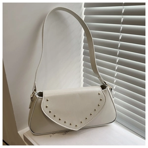 Close-up of cream PU leather baguette bag with gold studs and V-shaped flap