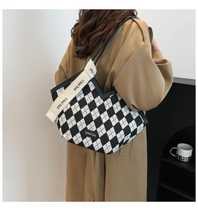 Detail of checkered tote bag with wide canvas strap and brand label for daily use