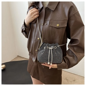 Detail of a black bucket bag with silver rhinestones and elegant pearl drawstring accents