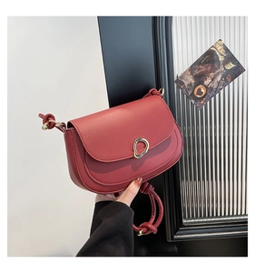 Detail of burgundy saddle bag showing gold buckle and stylish hand-woven knot strap