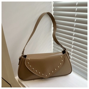 Close-up of brown vintage leather shoulder bag featuring decorative gold rivet studs