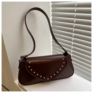 Detail view of coffee brown faux leather underarm bag with gold rivet trims on V-shaped flap