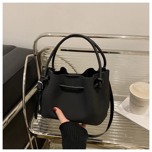 Detail of minimalist matte black bucket bag with drawstring and dual carry handles