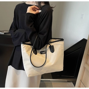 Detailed view of the large capacity tote bag featuring black strap and fashion patch label