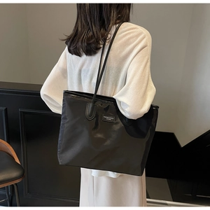Close-up of large black waterproof tote bag with fashion brand label and long shoulder straps