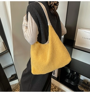 Side view of a yellow plush hobo bag with cream leather strap worn by a model