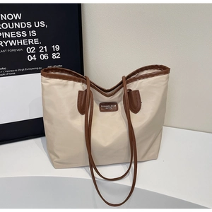 Detail of minimalist tote bag with large capacity, brown leather straps and cream nylon