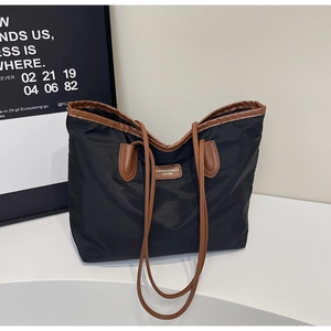 Close-up of black waterproof nylon tote bag with brown leather details and logo