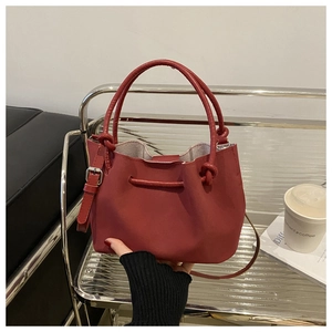 Detail of red pleated bucket bag with round handles and adjustable shoulder strap