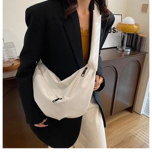 Close-up of white pebble leather crossbody bag with contrasting black zipper detailing