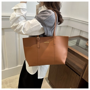 Gros plan détaillé du sac cabas en simili cuir marron montrant la texture et le logo doré