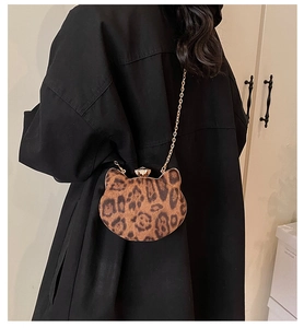 Detail of leopard print cat-shaped mini bag with gold chain strap on model shoulder