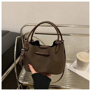 Detail of vintage pleated dark brown bucket bag with rolled top handles and slim strap