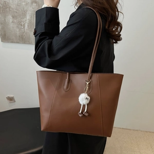 Brown leather tote bag with monster charm and shoulder straps for women's daily commute
