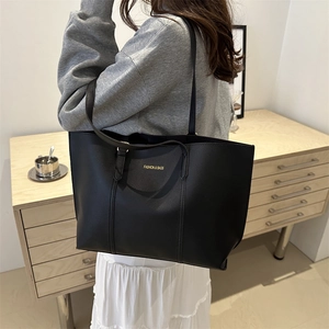 Grand sac cabas en cuir noir avec lettrage doré porté par un mannequin vue de côté