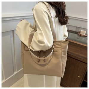 Detail of beige nylon tote bag featuring side pockets and adjustable shoulder straps