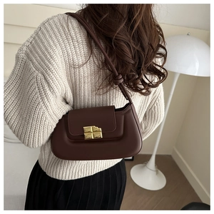 Detail of a dark brown leather baguette bag with a gold chocolate-style metal buckle