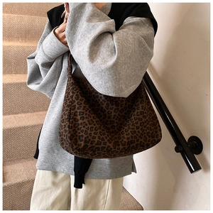 Detailed close-up of large leopard print hobo bag with canvas texture and long shoulder strap