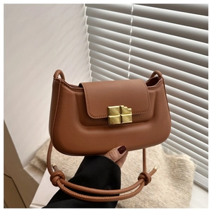 Detail of caramel puffer crossbody bag featuring a unique gold chocolate block clasp
