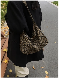 Chic leopard print bucket bag styled with black coat on an autumn street background