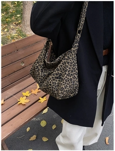Sac hobo en toile léopard porté à l'épaule dans un décor de parc automnal