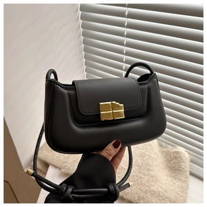 Detail of black matte leather shoulder bag featuring unique gold chocolate-bar buckle closure